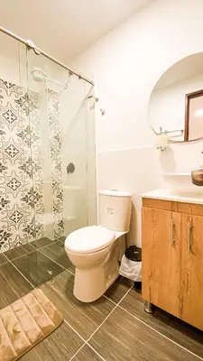 a bathroom with a toilet and a glass shower at OCASSO JARDIN APARTAMENTO TURPIAL in Jardin