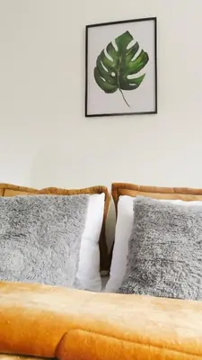 a bed with two pillows and a picture on the wall at OCASSO JARDIN APARTAMENTO TURPIAL in Jardin
