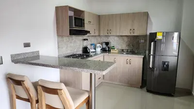 a kitchen with a stainless steel refrigerator and wooden cabinets at OCASSO JARDIN APARTAMENTO COLIBRÍ in Jardin