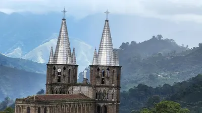a church with two towers with mountains in the background at OCASSO JARDIN APARTAMENTO COLIBRÍ in Jardin