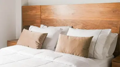 a bed with white pillows and a wooden headboard at OCASSO JARDIN APARTAMENTO GALLITO DE ROCA in Jardin