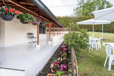 a patio with flowers and chairs and an umbrella at Finca Villa Isanella, Santuario, Antioquia in Santuario