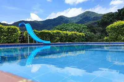 a blue slide in a swimming pool with mountains in the background at Eco Cabaña San Carlos Ant in San Carlos
