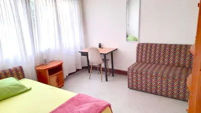 a room with a bed and a table and a chair at Hostal Saveva Para Grupos Familias Estudiantes y Deportistas in Medellín