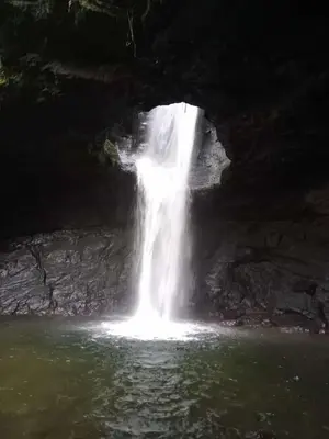 a waterfall in a cave next to a body of water at PaloSanto, Casa Rural in Jardin