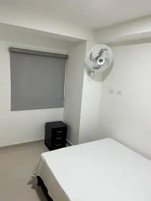 a bedroom with a white bed and a fan at Ubicación Perfecta en Laureles y Confort Total in Medellín