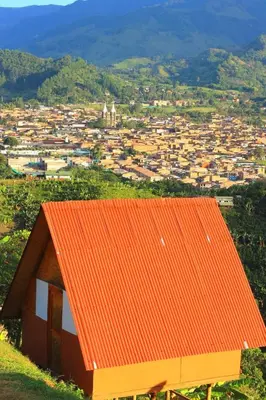 an orange roofed house on a hill with a city at Cabañas Villa Loe in Jardin