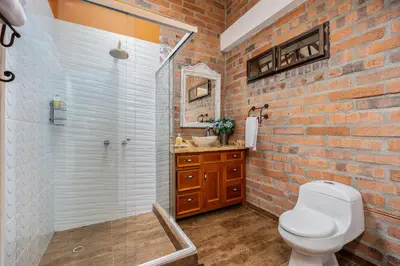 a brick bathroom with a toilet and a shower at AEROPUERTO-Rionegro- MONTEOLIVO COLONIAL in Rionegro