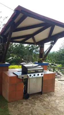 a barbecue grill with an umbrella on a patio at AEROPUERTO-Rionegro- MONTEOLIVO COLONIAL in Rionegro