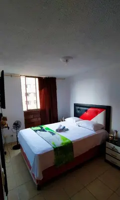 a bedroom with a large bed with red and green pillows at apartamento centro de la ciudad in Medellín