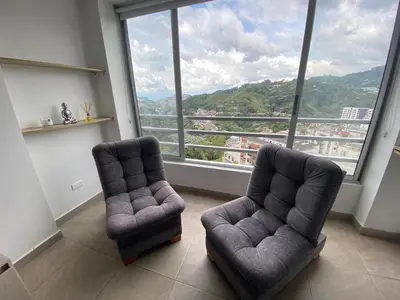 a living room with two chairs and a large window at Apartamento Mirador De Castilla in Manizales