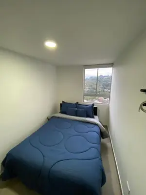 a small bedroom with a blue bed and a window at Apartamento Mirador De Castilla in Manizales