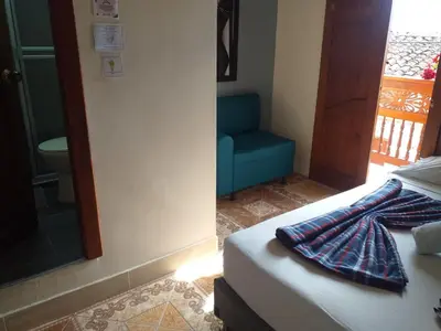 a bedroom with a bed and a blue chair at HOSTAL LA CASA DE LOS SUEÑOS in Jardin