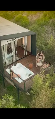 two people sitting in a hot tub on a deck at Cabañas para parejas cerca a Medellín - LUUM By Roots Rentals in Marinilla