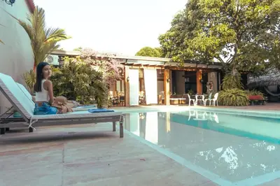 a woman sitting on a chair next to a swimming pool at casa lumka hotel boutique spa in Mariquita