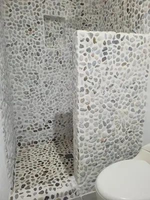 a bathroom with a toilet and a wall of rocks at casa lumka hotel boutique spa in Mariquita