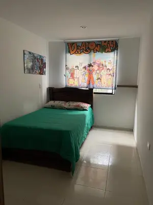 a bedroom with a green bed and a painting on the wall at Amplio apartamento en Niquia in Bello