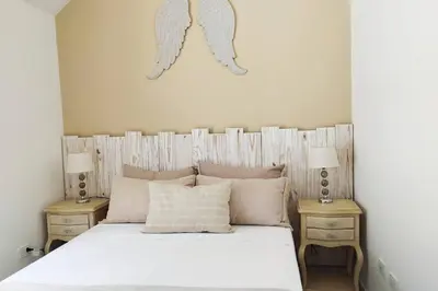 a bedroom with a bed with white sheets and two tables at Apto Nuevo, Tranquilo, Bonito, 5 min Plaza Principal in Guatapé