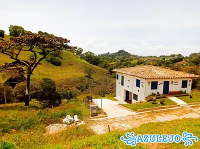 a small white house in a field with a hill at AZULEJO, Casa hotel campestre in Jericó