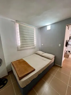a small bedroom with a bed with a window at Laurel de Florida Apto in Medellín