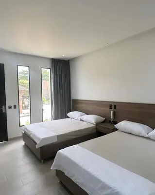 a hotel room with two beds and two windows at Hotel La Casona San Sebastian in Doradal