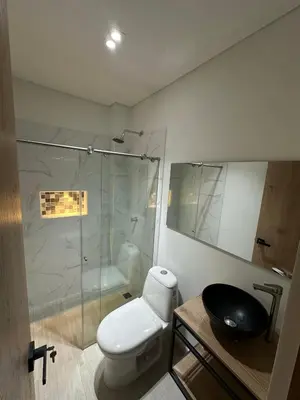 a bathroom with a toilet and a glass shower at Hotel La Casona San Sebastian in Doradal