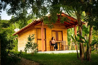 a woman sitting on a chair in front of a cabin at Hotel Campestre La Francesina in Betania