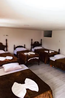 a room with four beds and a flat screen tv at Hotel Campestre La Francesina in Betania