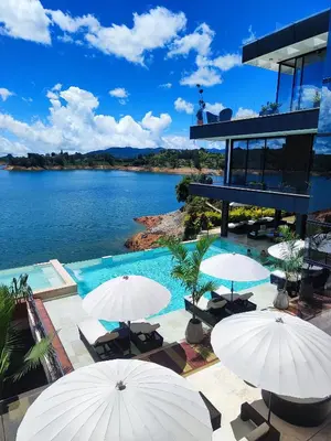 a resort with a pool and umbrellas and a lake at Vivanti Resort in Guatapé