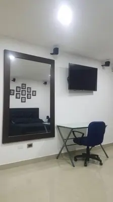 a room with a mirror and a chair and a television at Hospedajes Pilarica in Medellín