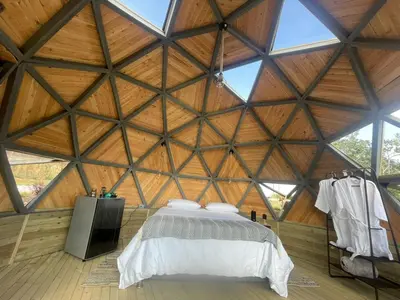a room with a bed in a large wooden building at Vitta Glamping in Rionegro
