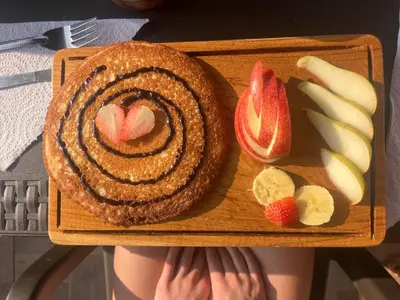 a wooden plate with a cake and fruit on it at Hostal Del Cielo in Medellín