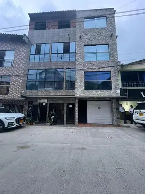 a large brick building with cars parked in front of it at Apartamentos amueblados, zona céntrica-Cisneros- antioquia in Cisneros
