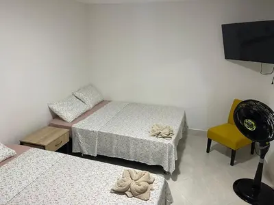 a room with two beds and a tv and a chair at Apartamentos amueblados, zona céntrica-Cisneros- antioquia in Cisneros