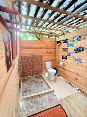 a bathroom with a toilet in a wooden wall at Glamping Colibrí, bosque vecino y vista a la montaña al mismo tiempo in Jardin