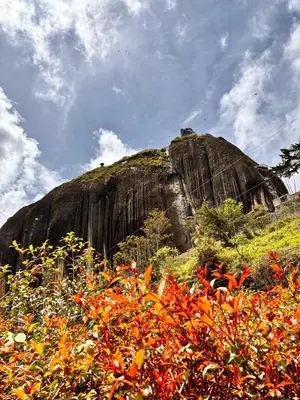 a large rock on top of a hill with flowers at HOSPEDAJE VILLA SAMARA --- cerca de la piedra -- GUATAPÉ in Guatapé