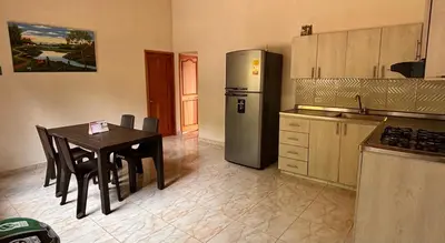 a kitchen with a table and a stainless steel refrigerator at HOSPEDAJE VILLA SAMARA --- cerca de la piedra -- GUATAPÉ in Guatapé