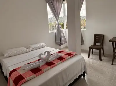 a bedroom with a bed with two swans towels at HOSPEDAJE VILLA SAMARA --- cerca de la piedra -- GUATAPÉ in Guatapé