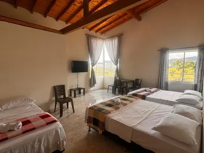 a bedroom with two beds and a tv and a window at HOSPEDAJE VILLA SAMARA --- cerca de la piedra -- GUATAPÉ in Guatapé