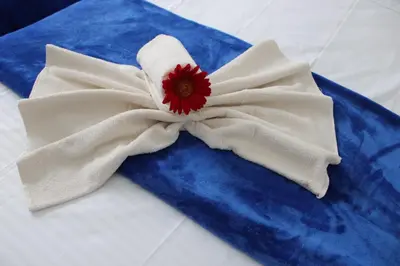 a white and blue napkin with a red flower on it at Absolute Hotel & Hostel Boutique in Medellín
