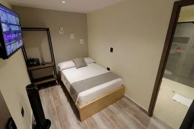 a small bedroom with a bed and a television at Casa Moderna Laureles con Jacuzzi y 7 Baños in Medellín