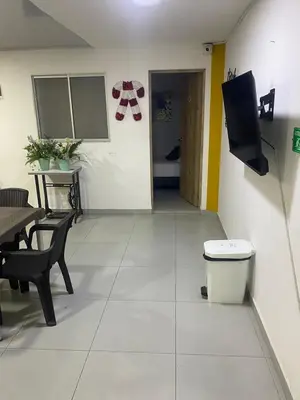 a living room with a table and a tv on a wall at Hotel Boutique San Joaquin Plaza in Medellín