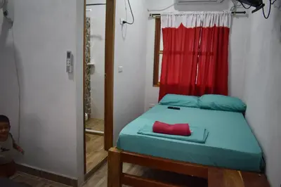 a small bedroom with a bed with a red curtain at Shaddai restaurante y hospedaje in Puerto Triunfo