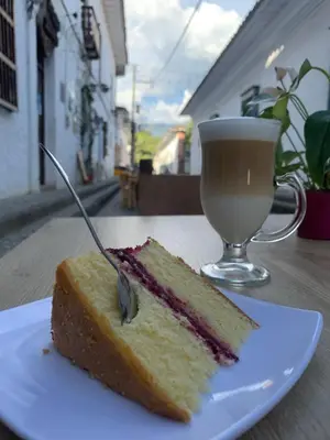 a piece of cake on a plate next to a cup of coffee at Casa hotel Dulce Candelaria in Santa Fe de Antioquia