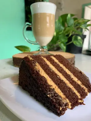 a slice of chocolate cake on a plate with a drink at Casa hotel Dulce Candelaria in Santa Fe de Antioquia