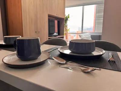 two cups and saucers on a table with spoons at Espectacular apt moderno en el poblado by Hoost in Medellín