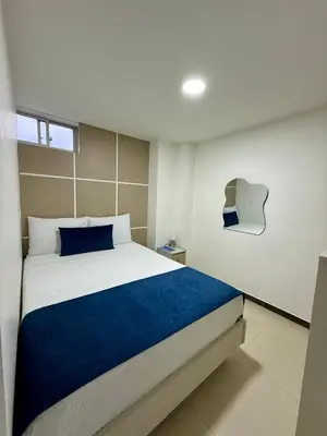 a bedroom with a large bed with a blue blanket at Hotel Boutique Paralela Real. in Manizales