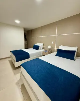 two beds in a room with blue and white at Hotel Boutique Paralela Real. in Manizales