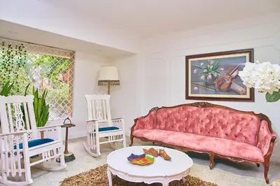 a living room with a pink couch and two chairs at Hotel Boutique Fiorentina Medellín in Medellín