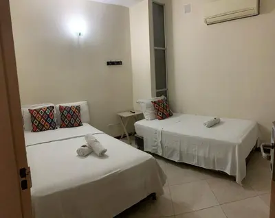 a room with two beds with white sheets at Hotel Tierra Santa Santa Fe de Antioquia in Santa Fe de Antioquia